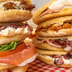 Ecco cosa sono le tigelle: dischi di pane morbido farciti con salumi, formaggio, verdure e salse, un vero piacere per il palato.