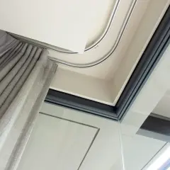 Szyna sufitowa aluminiowa płynnie prowadzi szare zasłony, tworząc elegancką przestrzeń przy dużym oknie.