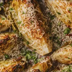 Grilla spetskål med parmesan och citron. Vackert gyllene och krispiga bitar av kål, strödda med färsk persilja och riven ost.
