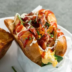 Herzhaftes Eggdrop Sandwich mit knusprigem Speck, Rührei, Käse und Ketchup, serviert mit geröstetem Käse-Toast.