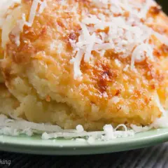 Gebackene Gnocchi alla Romana, goldbraun und mit geriebenem Parmesan bestreut, auf einem grünen Teller.