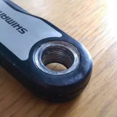 Close-up of a Shimano crank arm showing the threaded hole for pedal installation. This detail is crucial for understanding the correct mtb pedal thread size.