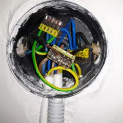 Widoczne przewody elektryczne w puszce, połączone złączkami. Brak zera w gniazdku może być przyczyną problemów z instalacją.