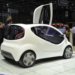Białe, futurystyczne auto, które mogłoby być najtańszym autem na świecie, prezentowane na wystawie.