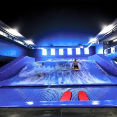 Surf sur une vague artificielle à Paris pour des sensations fortes. Deux personnes s'amusent sur la planche.