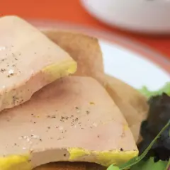 Tranches de foie gras poêlé, assaisonnées de sel et poivre, sur une galette. Le temps de cuisson foie gras bain-marie est crucial pour cette texture.