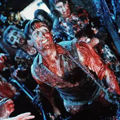 Krwawy mężczyzna otoczony przez zombie. Scena pełna grozy, idealna dla fanów **horrory 18+**.