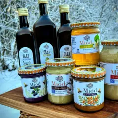 Słoiki z miodem i butelki z olejem na tle zimowego krajobrazu. Miód pitny trójniak ile procent? Sprawdź etykiety!