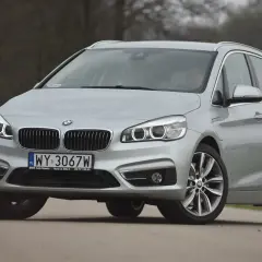 Srebrne bmw 218i na drodze, z przodu widoczna atrapa chłodnicy i reflektory.