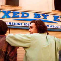 Tre amici guardano un negozio con insegna "MIXED BY ERRY".