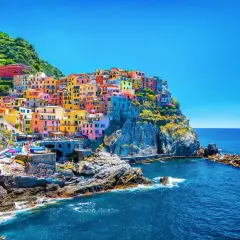 Village coloré accroché à la falaise, vue sur la mer bleue. Un gîte Cinque Terre parfait pour des vacances inoubliables.
