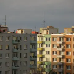 Bloki mieszkalne z balkonami, na dachu jeden z nich widnieje napis "50". W tle inne budynki, niebo zachmurzone. Warto pamiętać o fundusz remontowy przepisy.