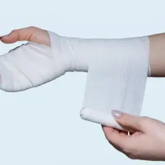 Instrukcja, jak usztywnić nadgarstek w domu, pokazująca owijanie ręki bandażem.