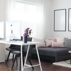 Ein helles Arbeitszimmer mit Schreibtisch, zwei Computern und einem gemütlichen Sofa, das zum Einrichten einlädt.
