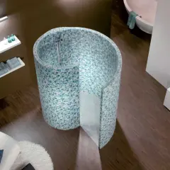 Une douche escargot aux mosaïques bleues et vertes, avec une baignoire et un fauteuil blanc dans une salle de bain moderne.