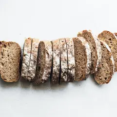 Rebanadas de pan de centeno rústico, con una corteza crujiente y miga aireada, listas para disfrutar.