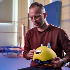 Mann erklärt, wie muss ein Fahrradhelm sitzen: Kinderhelm mit Ohren, gut angepasst und sicher.
