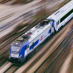 Pędzący pociąg PKP Intercity EU160 na torach, rozmyte tło sugeruje dużą prędkość.