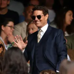 Tom Cruise w garniturze, machający do fanów. Ciekawe, ile zarabia Tom Cruise za takie wystąpienia.