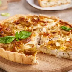 Pyszna tarta z porem, kurczakiem i serem, ozdobiona listkami bazylii. Idealna na obiad lub kolację.