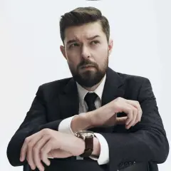 Remigiusz Mróz, znany pisarz, w eleganckim garniturze, z zamyśloną miną. Może planuje kolejną premierę książki, a może wizytę u dentysty?