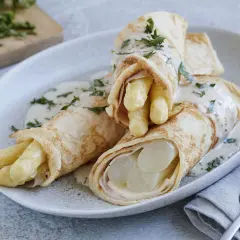 Pfannkuchen mit Spargel und Schinken, übergossen mit einer cremigen Sauce und garniert mit Petersilie.