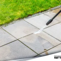 Mycie kostki brukowej na starym betonie myjką ciśnieniową. Woda spływa po płytach, przywracając im blask.