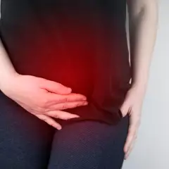 Donna con mani sull'addome, evidenziato da un bagliore rosso, che suggerisce un disagio come la pancia gonfia ovulazione.
