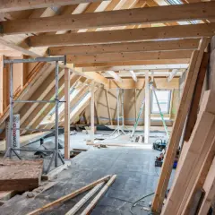 Chantier d'isolation des combles : charpente en bois, rouleaux d'isolant, échafaudages et matériaux de construction.