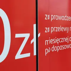 Na czerwonym tle biały napis "0zł" i lista opłat za konto, przelewy i kartę w Santander.
