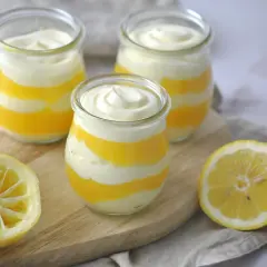 Schichtdessert in Gläsern, perfekt, wenn Sie Zitronenmelisse Creme selber machen möchten. Frische Zitronenhälften liegen daneben.
