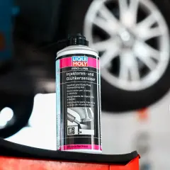 Puszka preparatu do czyszczenia wtryskiwaczy Liqui Moly na tle koła samochodu. Pomaga w demontażu zapieczonych elementów.