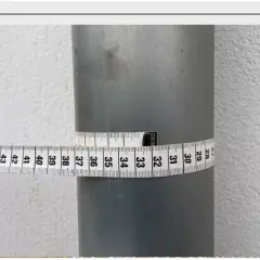 Miarka krawiecka owinięta wokół rury, pokazująca jej obwód. Odczyt wskazuje na średnicę około 32 cm.