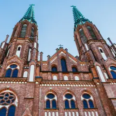 Imponująca ceglana bazylika z dwiema strzelistymi wieżami, ozdobiona oknami i detalami architektonicznymi. Jeden z najpiękniejszych kościołów w Polsce.