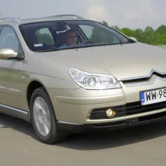 Złoty Citroen C5 kombi w ruchu drogowym. Kierowca za kierownicą. Wiele pozytywnych citroen c5 opinie potwierdza jego komfort.