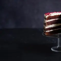 En läcker red velvet cake med lager av choklad och krämig frosting, dekorerad med röda pärlor.