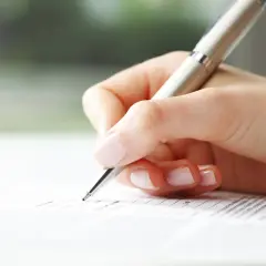 Dłoń pisze długopisem na dokumencie. To może być oświadczenie o zakończeniu najmu do us wzór.