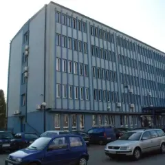 Budynek miejskiego ośrodka pomocy społecznej w Dąbrowie Górniczej, z zaparkowanymi samochodami przed wejściem.
