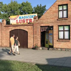 Para spaceruje obok budynku z napisem "Magiczne Lustra Łeba".