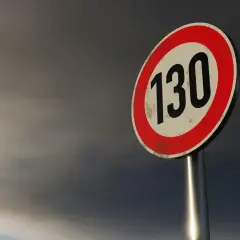 Znak ograniczenia prędkości 130 km/h na tle burzowego nieba, typowy dla autostrad w Niemczech.