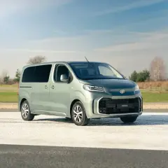 Nowy, zielony Toyota Proace na tle nieba i pól. Idealny do rodzinnych podróży i transportu.