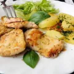 Smażony pstrąg łososiowy z ziemniakami i sałatą. Widok z góry na talerz z daniem.