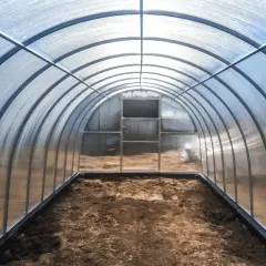 Wnętrze tunelu foliowego z łukowatym dachem z poliwęglanu, który pokazuje, czy poliwęglan można wyginać.