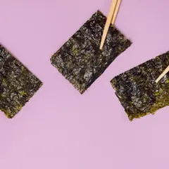 Tre fogli di alga nori, tenuti da bacchette, evidenziano le loro proprietà nutritive.