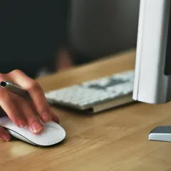 Dłoń trzymająca myszkę komputerową, gotowa do pracy przy komputerze.