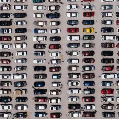 Wielki parking pełen europejskich marek samochodów, uporządkowanych w rzędy.