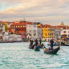 Gondoles glissant sur le Grand Canal, un jour d'octobre à Venise. Les façades colorées des palais se reflètent dans l'eau calme.