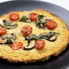 Deliciosa pizza de coliflor con queso derretido, champiñones y tomates cherry.