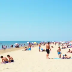 Tłum ludzi na piaszczystej plaży, szukających odpowiedzi na pytanie: gdzie najbliżej nad morze z Warszawy.