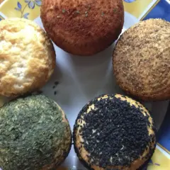 Pięć okrągłych serów na talerzu, jeden z czarnuszką, jeden z ziołami, jeden przypieczony, dwa naturalne. Idealne do przepisu na wędzony ser typu włoskiego.